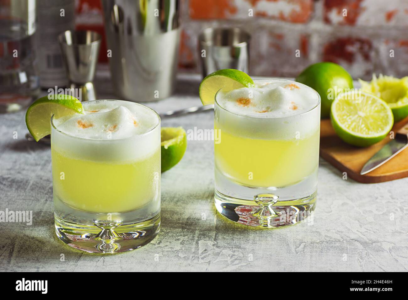 Pisco Sour Cocktails with Lime and Egg White Foam on Bar Top with Tools Stock Photo