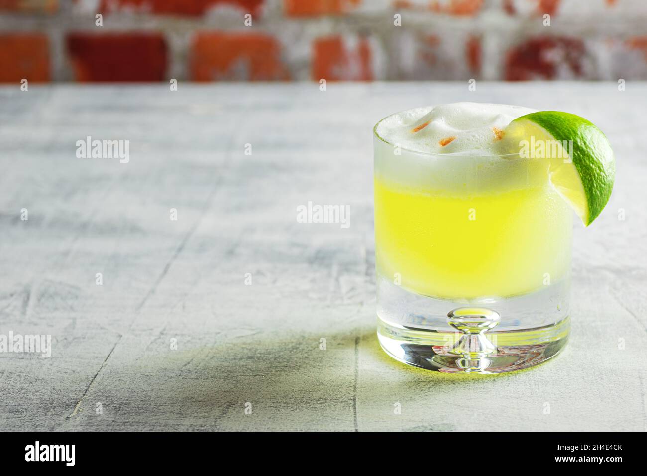 Pisco Sour Cocktail with Lime and Egg White Foam on Bar Top Stock Photo