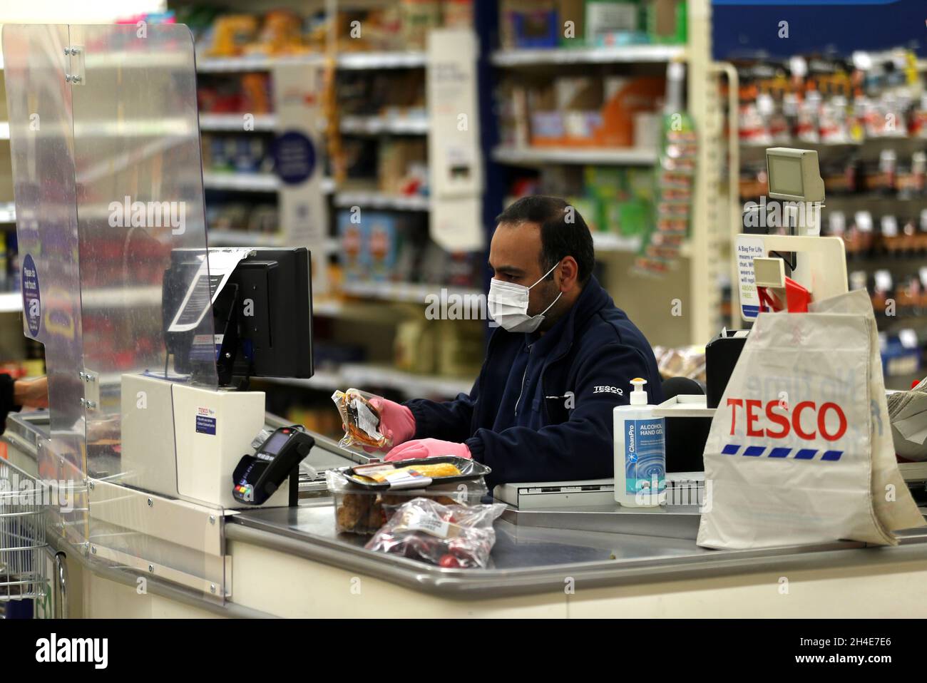 A Tesco supermarket cashier wearing protective face mask and gloves