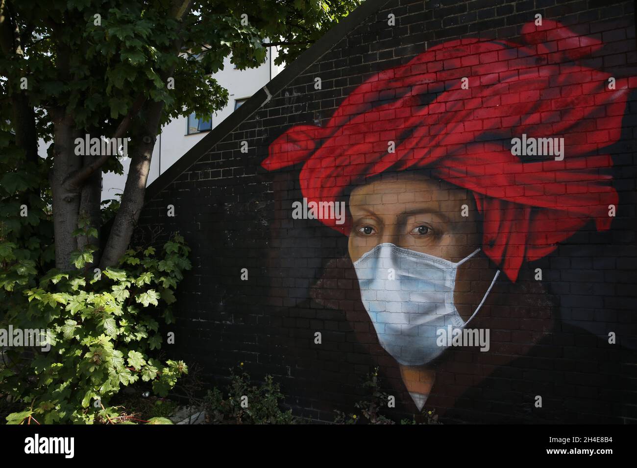 A mural in Ladywell, south east London, by street artist Lionel Stanhope depicting a painting by Flemish master Jan van Eyck wearing a protective face mask, as the UK continues in lockdown to help curb the spread of the coronavirus. Picture date: Friday May 8, 2020. Stock Photo