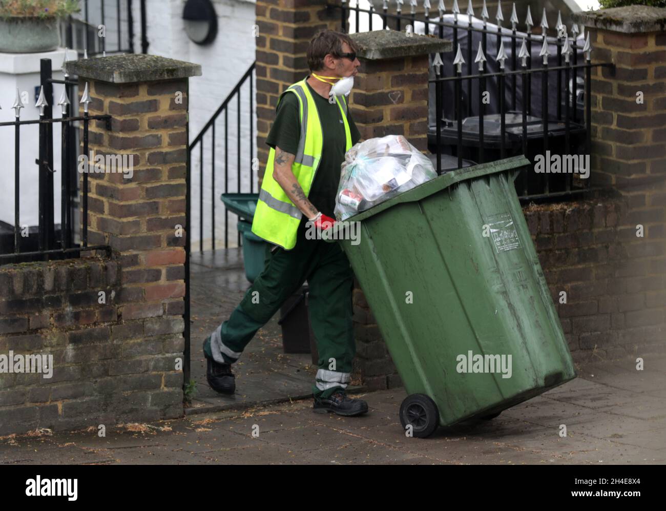 An Islington council refuse collector wearing a face mask clears the
