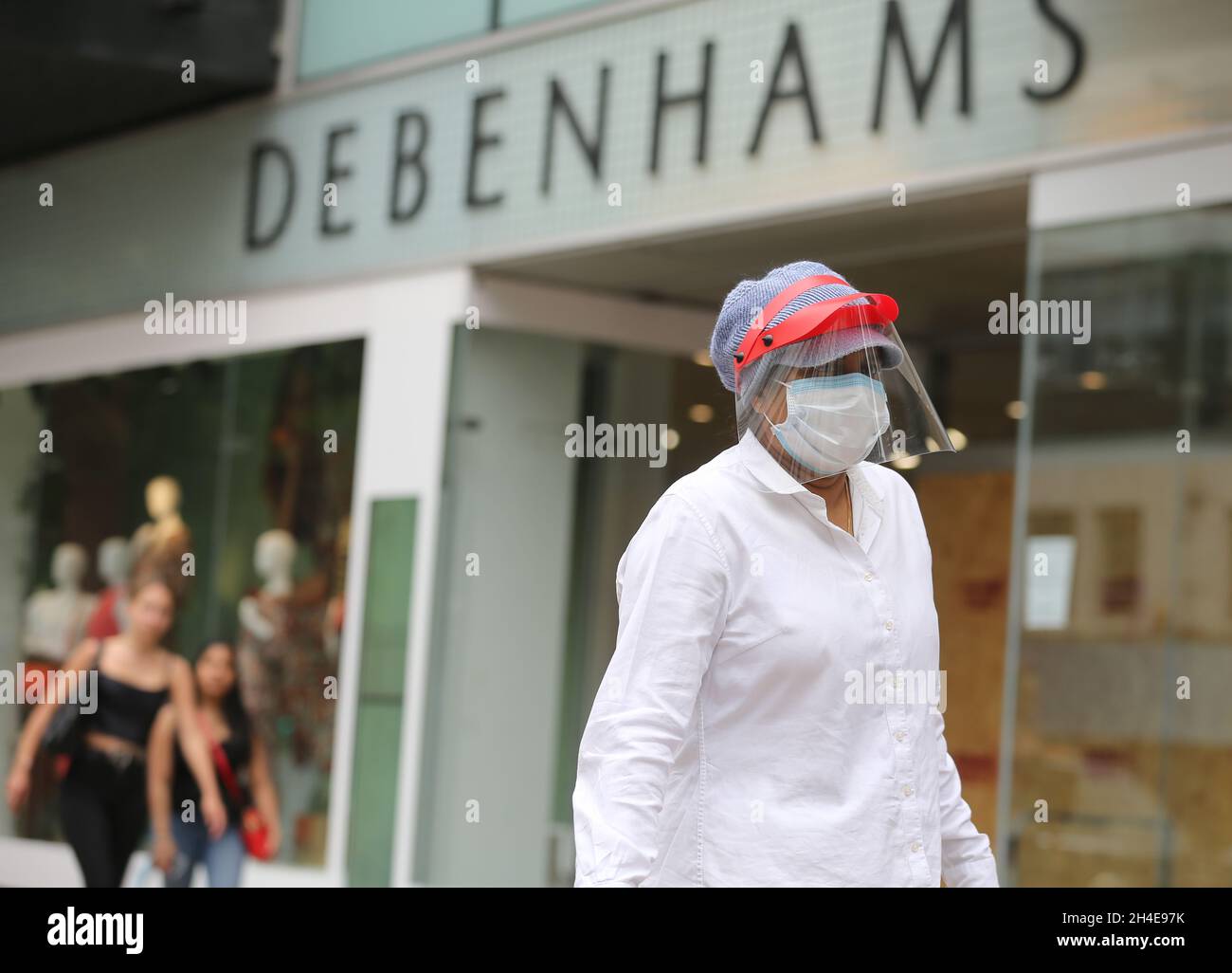 A shopper wearing a protective visor walks past a closed Debenhams store on Oxford Street, London, as non-essential shops in England open their doors to customers for the first time since coronavirus lockdown restrictions were imposed in March. Picture date: Monday June 15, 2020. Stock Photo