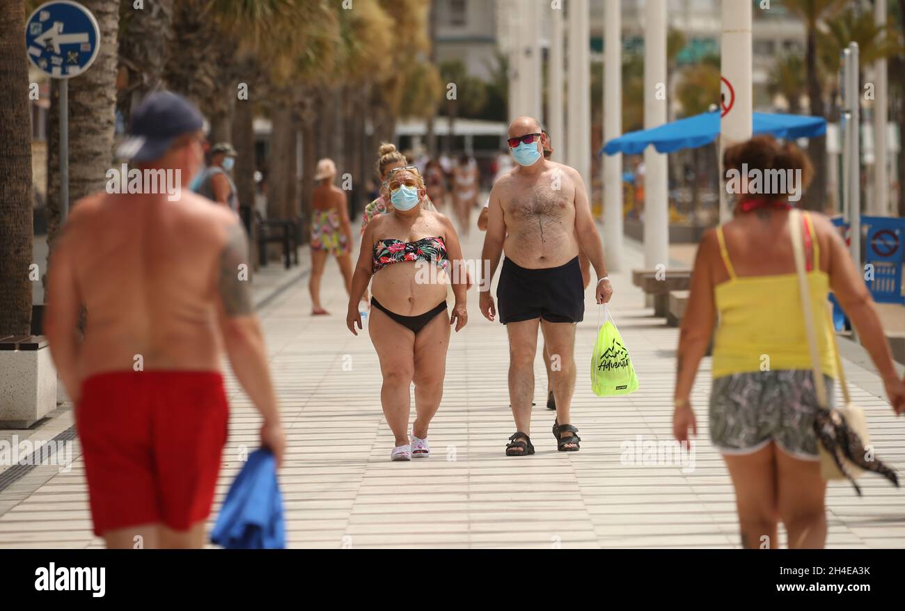 Tourists walk by the Levante beach in Benidorm, a seaside resort on the eastern coast of Spain, which remains almost empty following the UK government’s quarantine to all tourists that travel from Spain because of its high levels of COVID-19 cases. Picture date: Thursday July 30, 2020. Stock Photo
