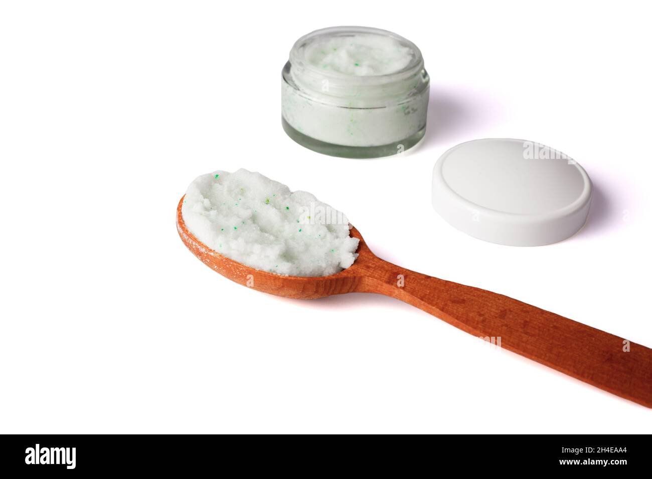 Body scrub with green crystals in wooden spoon. Homemade cosmetic for