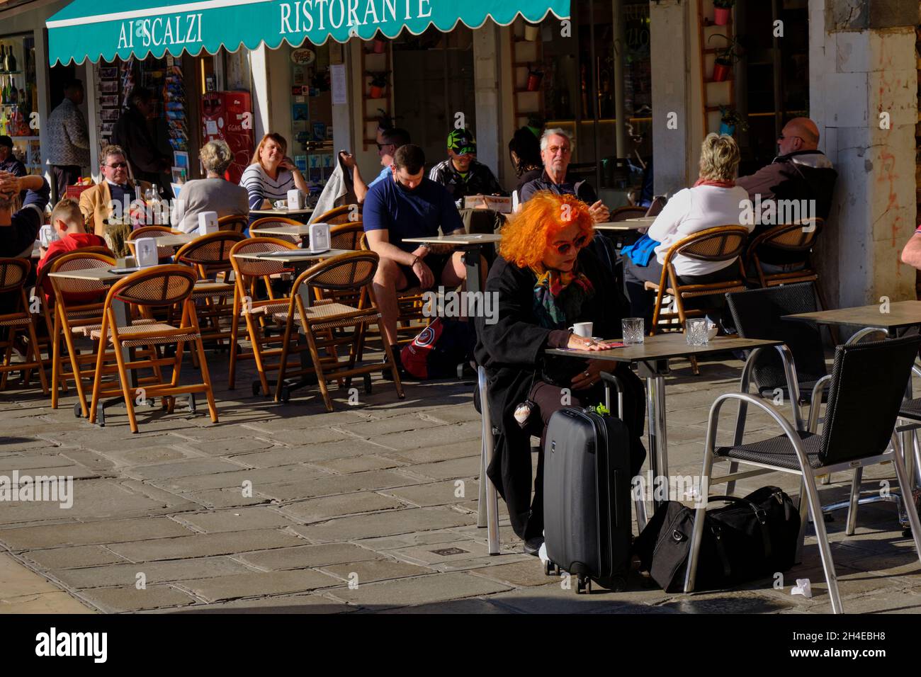 Elderly woman tourist with flaming red hair sitting at bar in Venice Italy Stock Photo