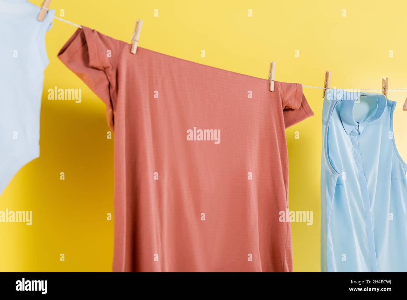 clean laundry hanging on rope on yellow background Stock Photo