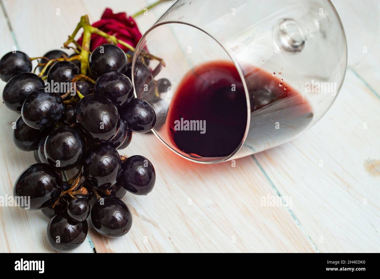 tilted glass of wine with black grapes on wood boards Stock Photo Alamy