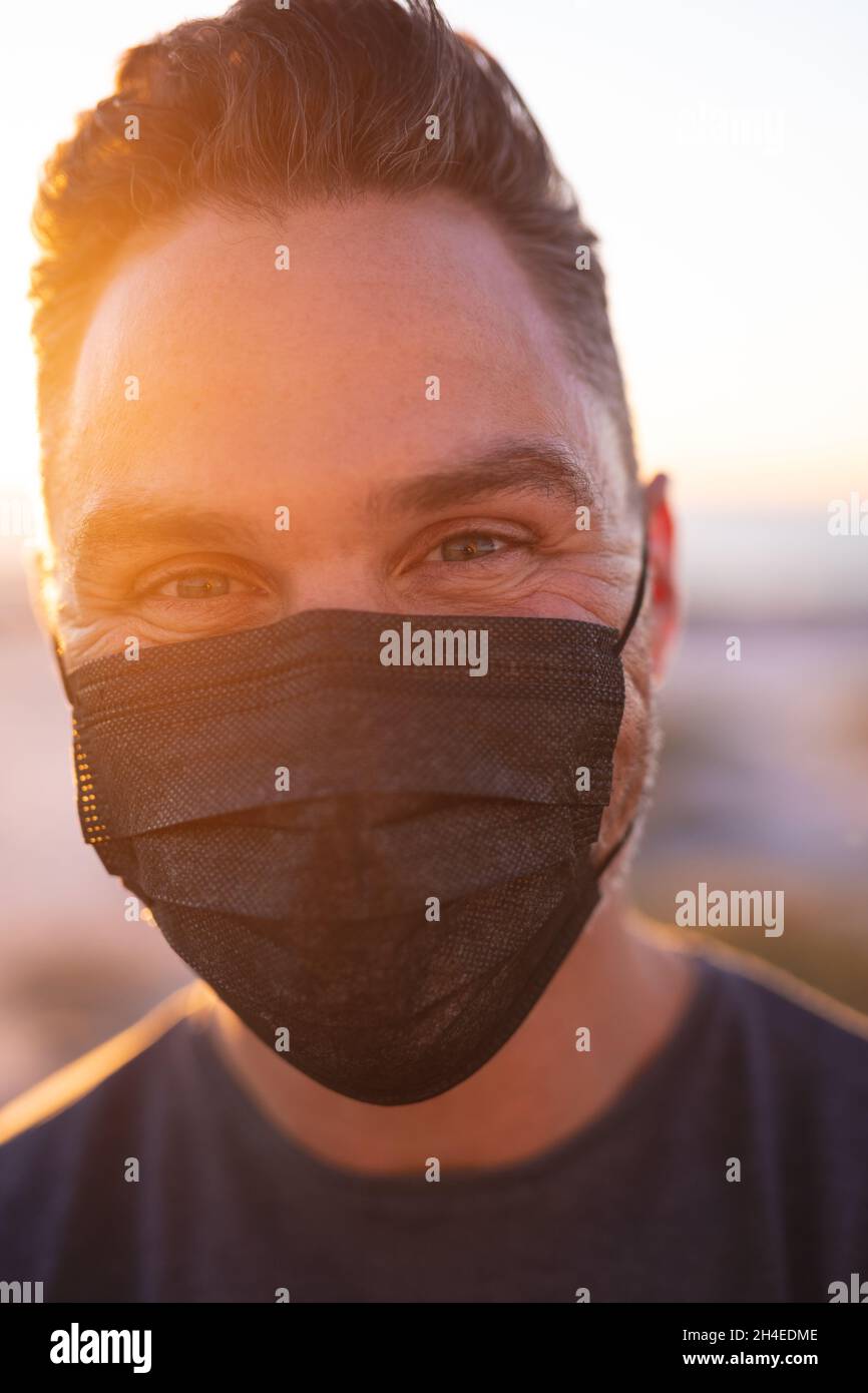 Portrait of caucasian man wearing face mask looking at camera at ...