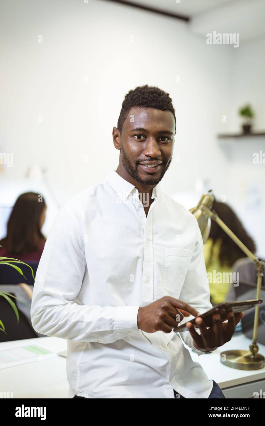 Portrait of smiling african american businessman using tablet looking ...