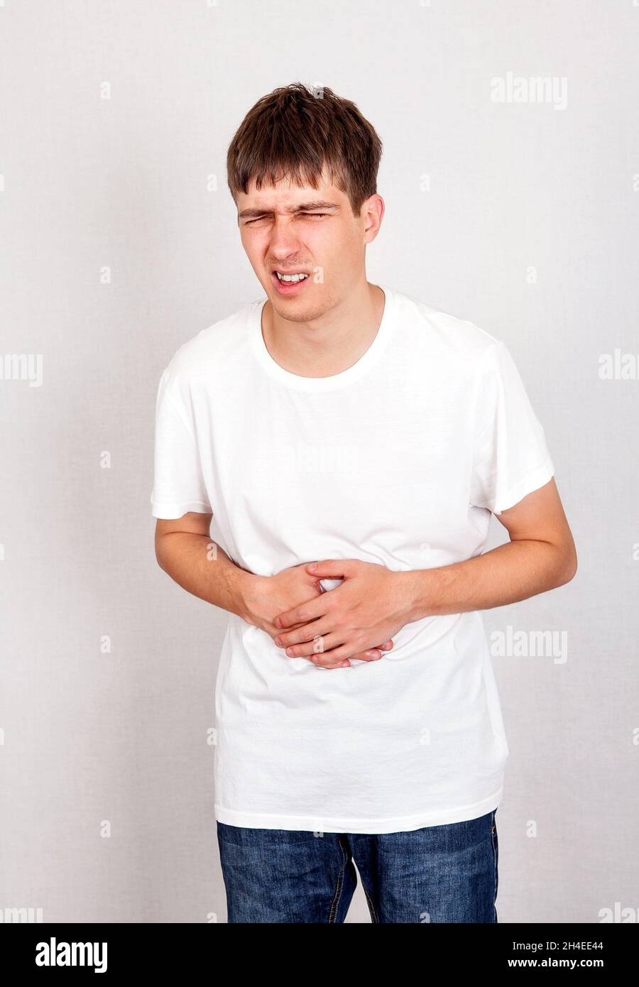 Young Man feels Stomach Ache on the White Wall Background Stock Photo