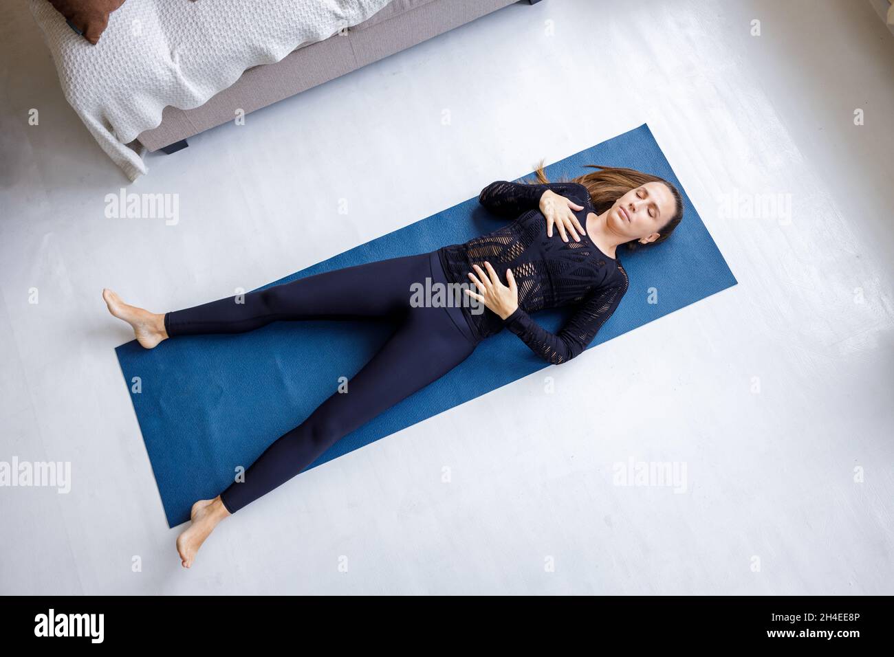 Young slim beautiful woman lying down on the mat in shavasana yoga pose Stock Photo