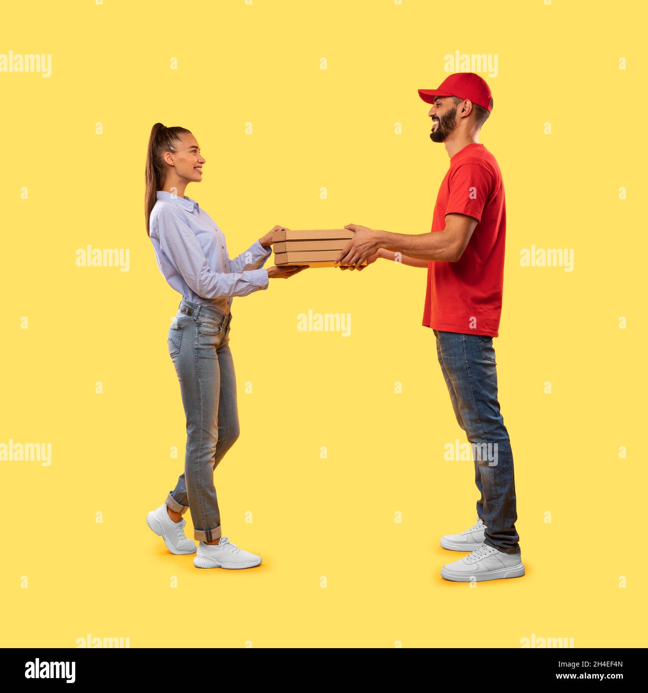 Arabic Courier Guy Giving Pizza To Female Over Yellow Background Stock Photo