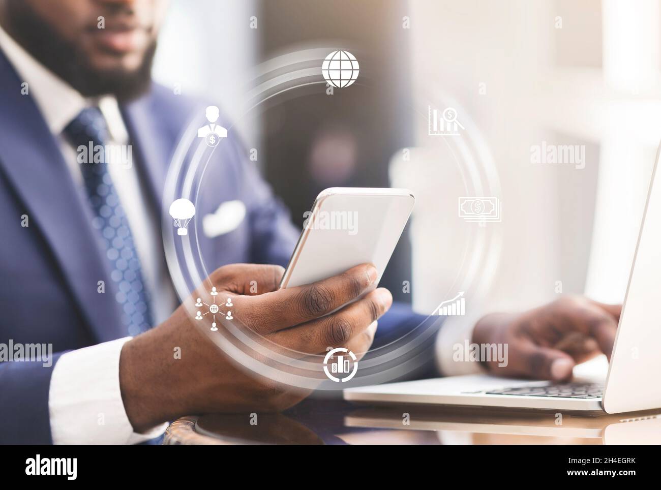 Young black man working in office with laptop and smartphone, collage with abstract icons at workplace Stock Photo