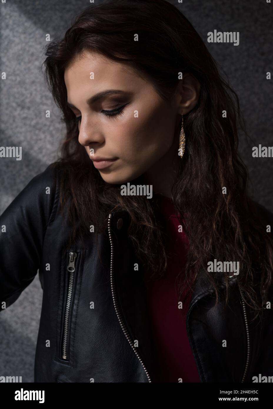 Portrait of a young woman in a black leather jacket standing in front ...