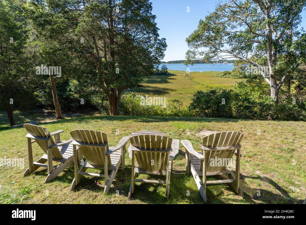 Four wooden adirondack chairs looking out towards the sea Stock Photo ...
