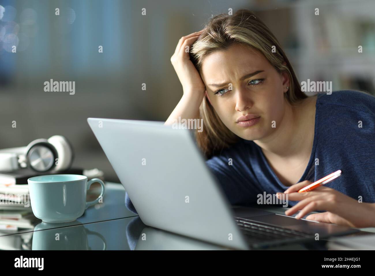 Frustrated student e-learning with a laptop in the night at home Stock Photo