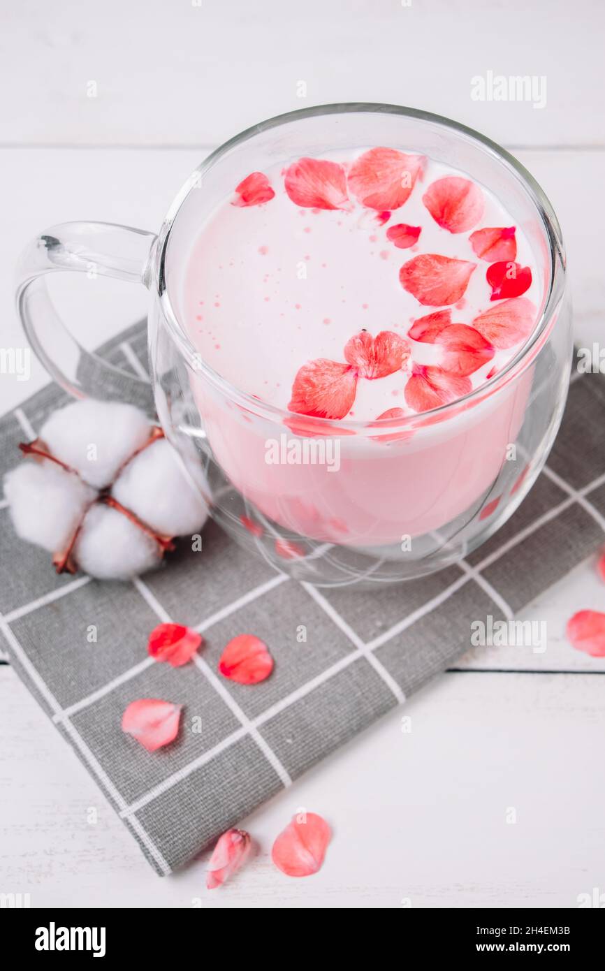 Pink matcha with rose petals on a white background. Transparent cup