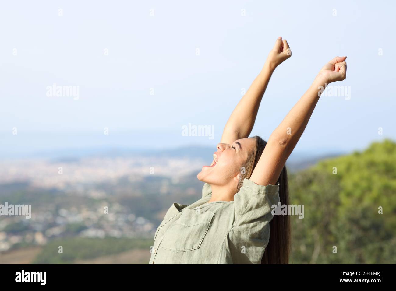 Profile of an excited teen celebrating raising arms outdoors Stock Photo