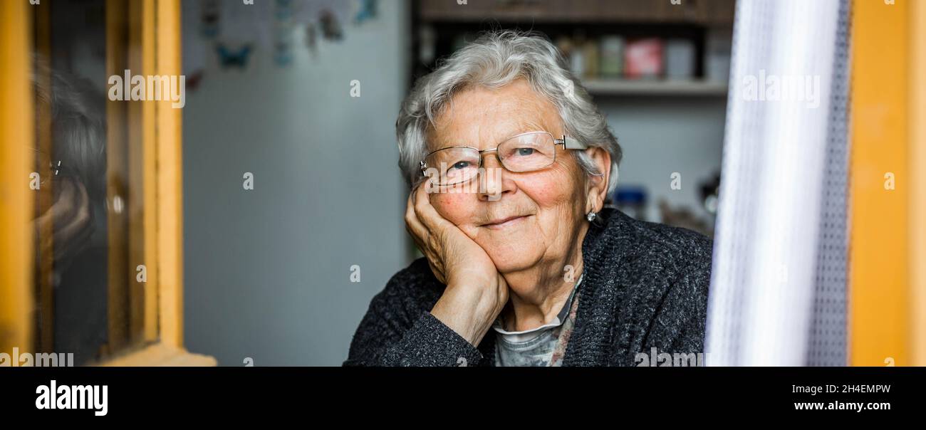 Lovely portrait of smilling grandmother by the window at a house Stock Photo
