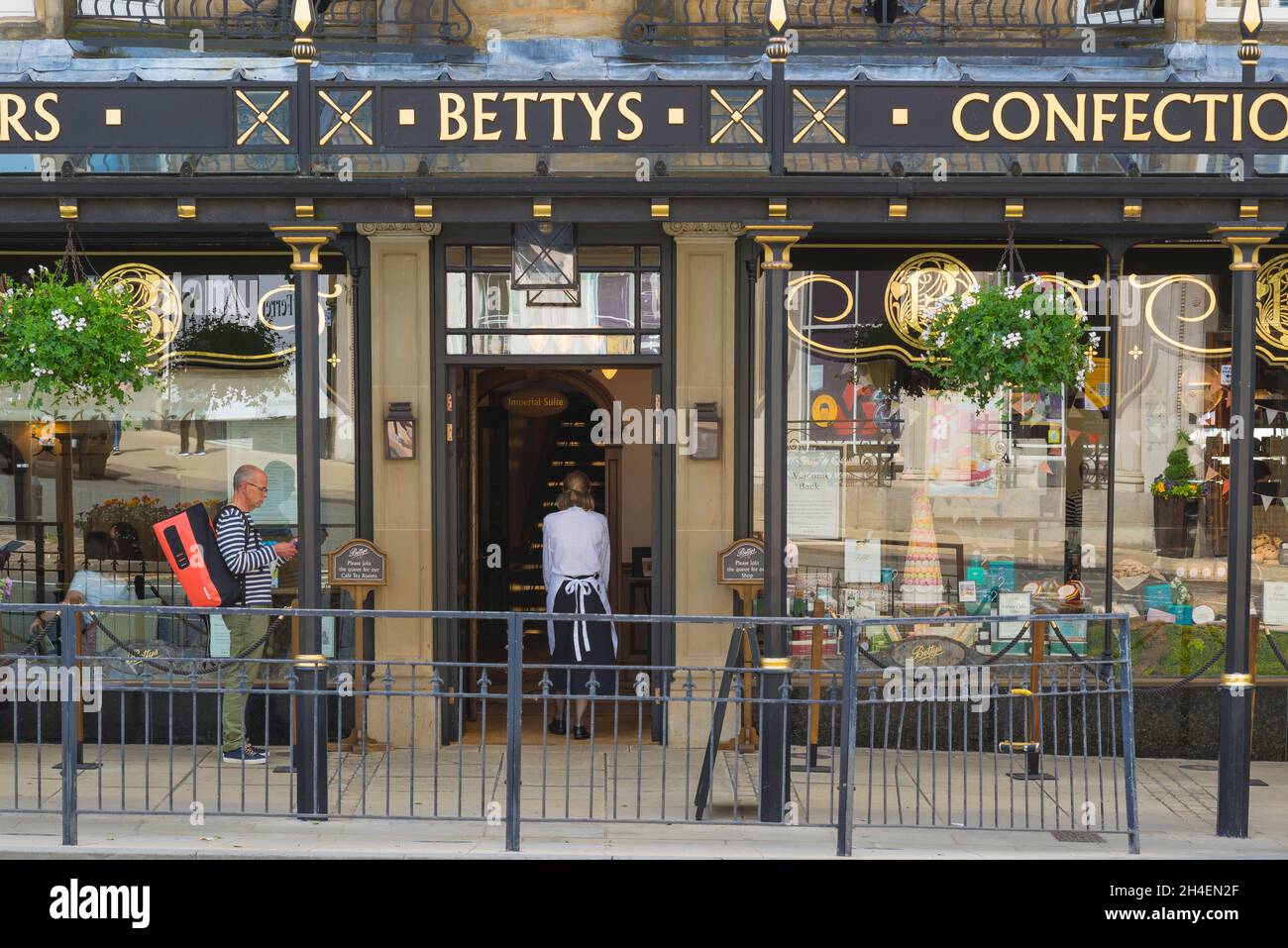 Bettys Harrogate, rear view of a waitress returning inside Bettys Cafe and Tea Rooms on Parliament Street, Harrogate, North Yorkshire, England, UK Stock Photo