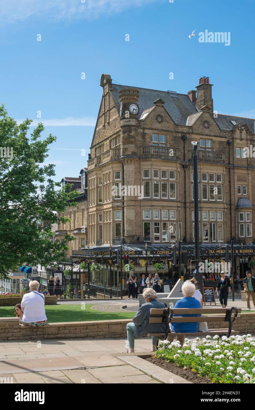 Harrogate people, view in summer of people relaxing in the Cenotaph Gardens and looking towards Bettys Cafe Tea Rooms in central Harrogate, England,UK Stock Photo