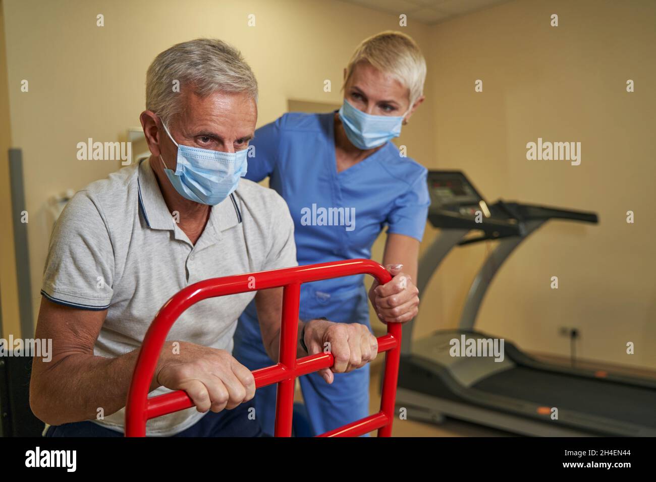Physiotherapist teaching disabled man to use walker at recovery center