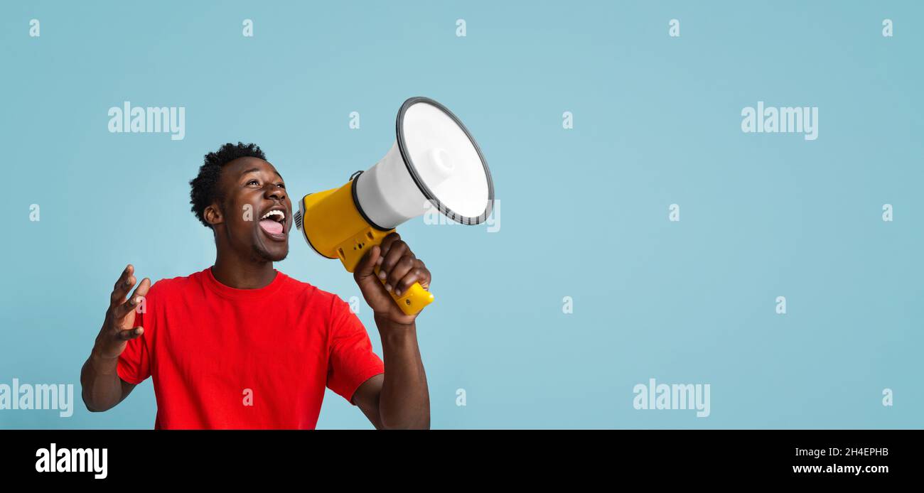 Emotional Young Black Guy Making Announcement With Megaphone In Hands Stock Photo