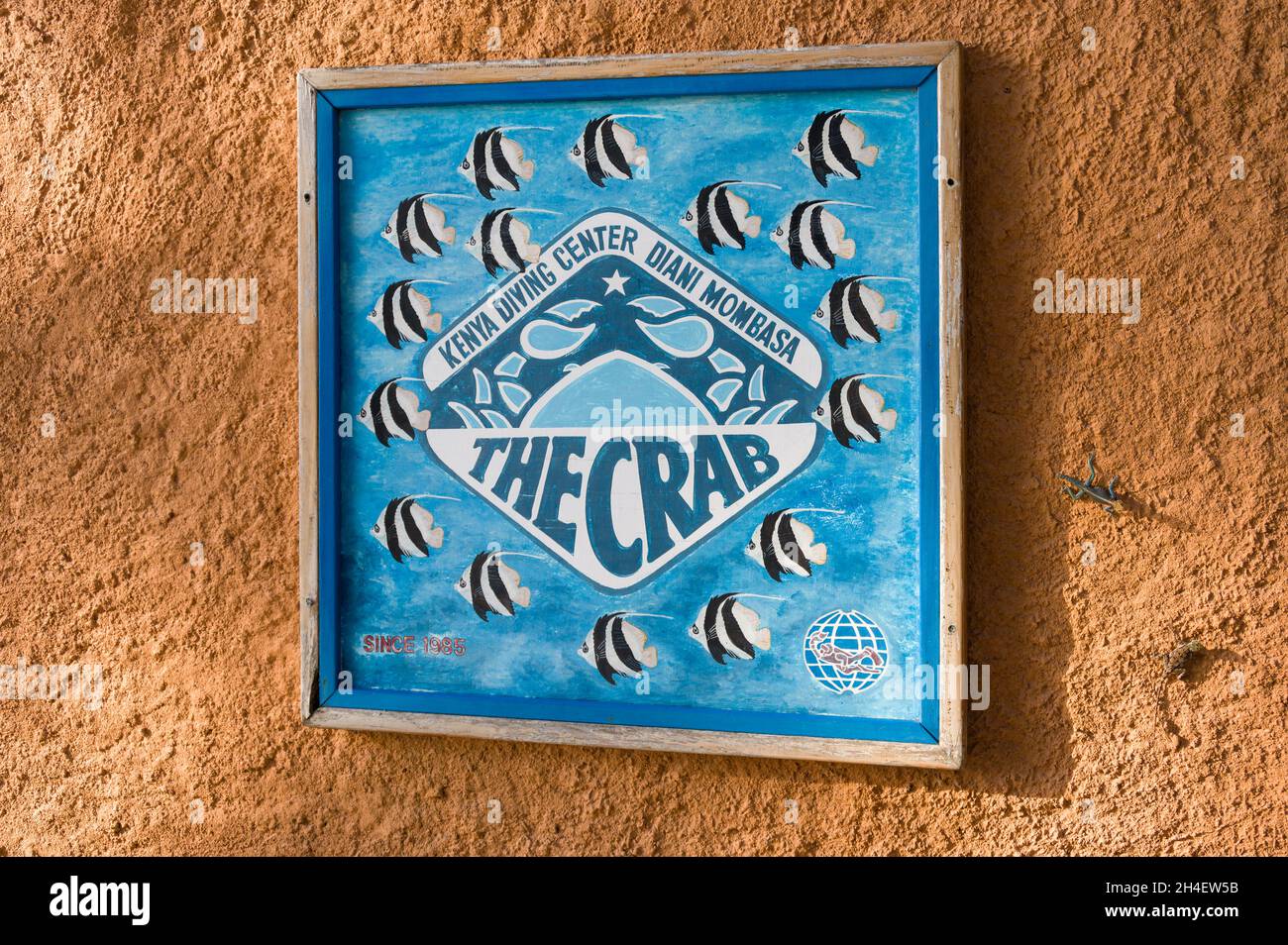 The Crab diving centre wooden painted sign on an orange stone wall, Diani, Kenya Stock Photo