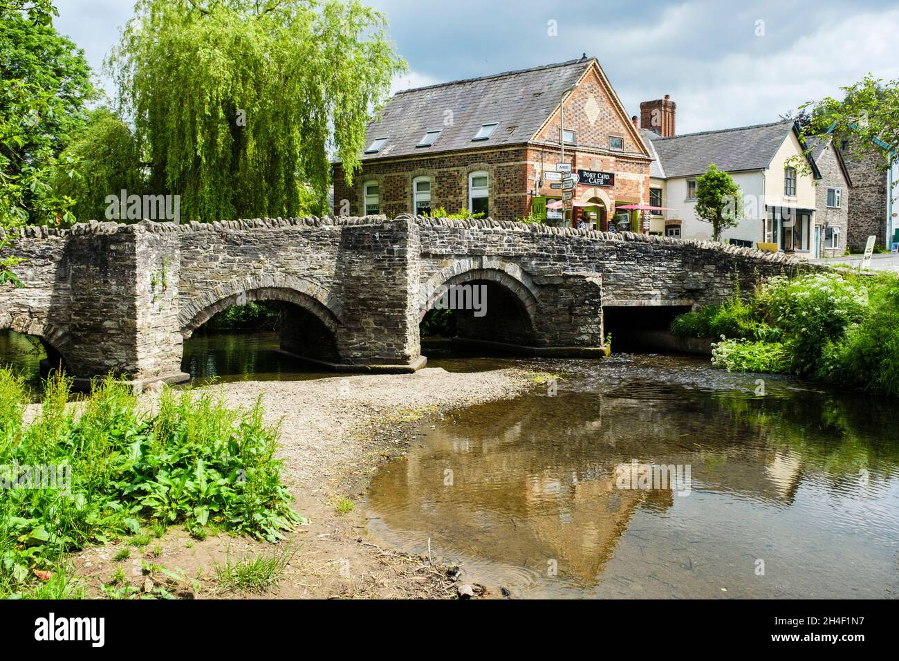 Packhorse bridge over River Clun in small village with Post Card cafe in Shropshire Hills Area of Outstanding Natural Beauty. Clun Shropshire England Stock Photo