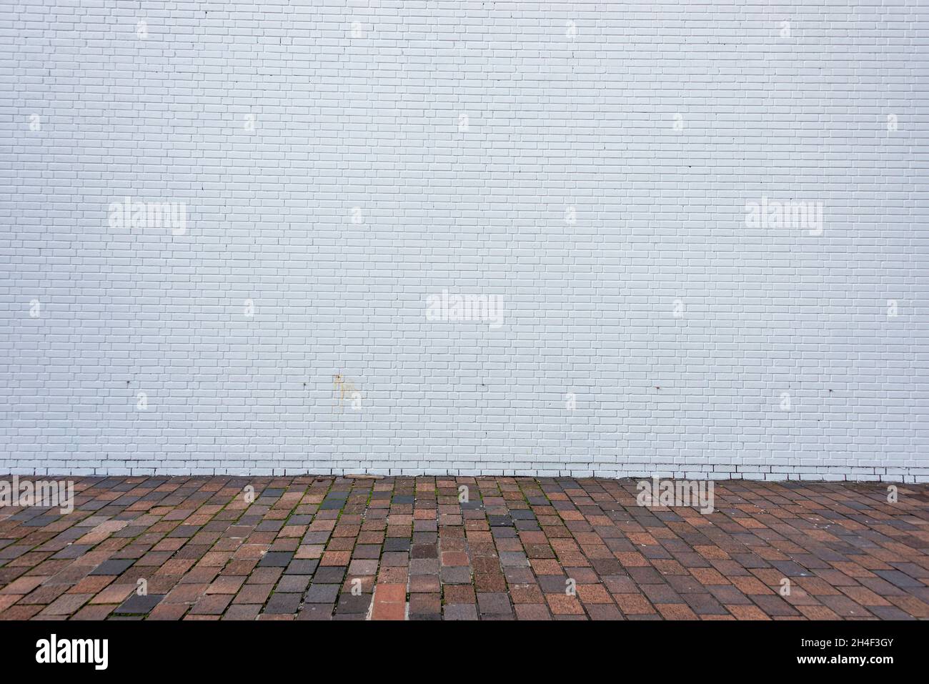 White wall with brick sidewalk Stock Photo