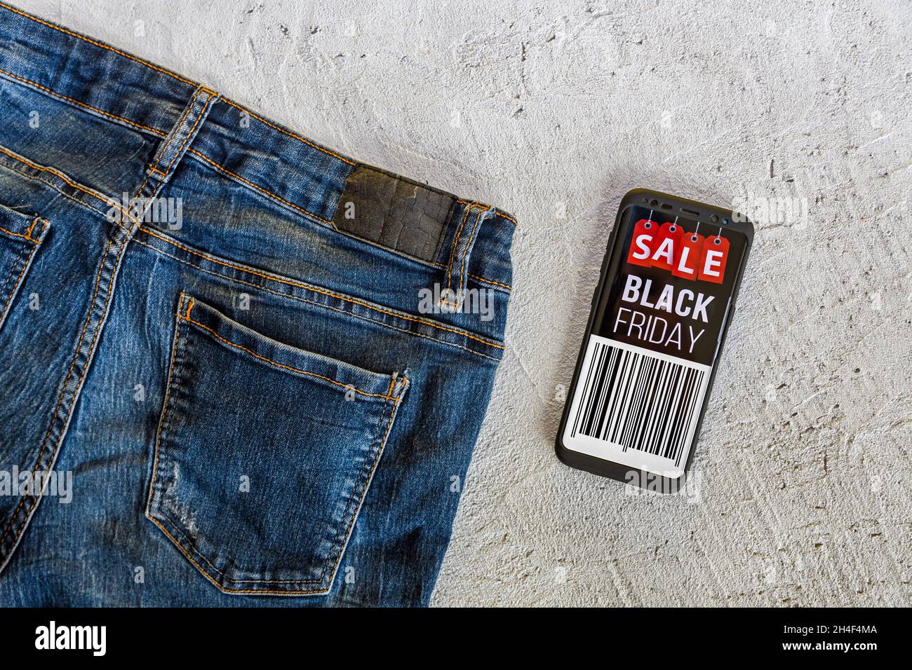Overhead of blue jeans and mobile phone black friday sale on screen Stock Photo - Alamy