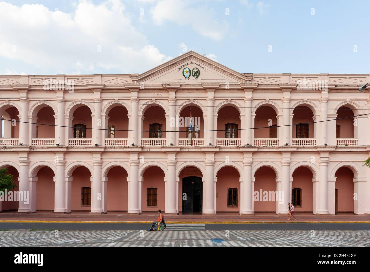 Asuncion, Paraguay. 10th March, 2010. View of a man in a wheelchair passing in front of the 'Centro Cultural de la Republica' (Cultural Center of the Republic) which operates in the building of the former 'Cabildo' (Town Council). The building was also place of the National Congress. It was built in 1844 to be seat of the Executive and Legislative Branch. Stock Photo