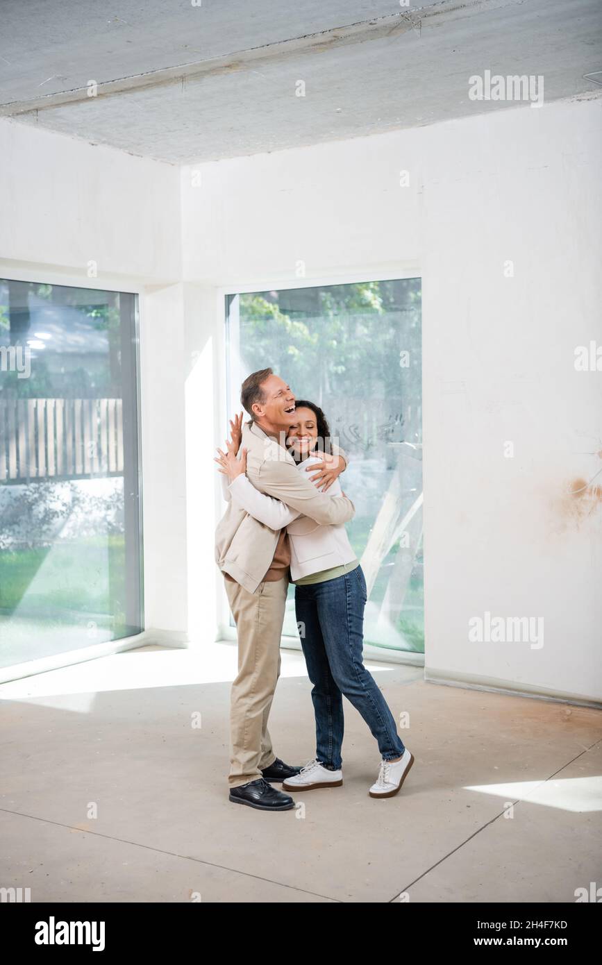 cheerful man hugging pleased african american wife in new house Stock ...