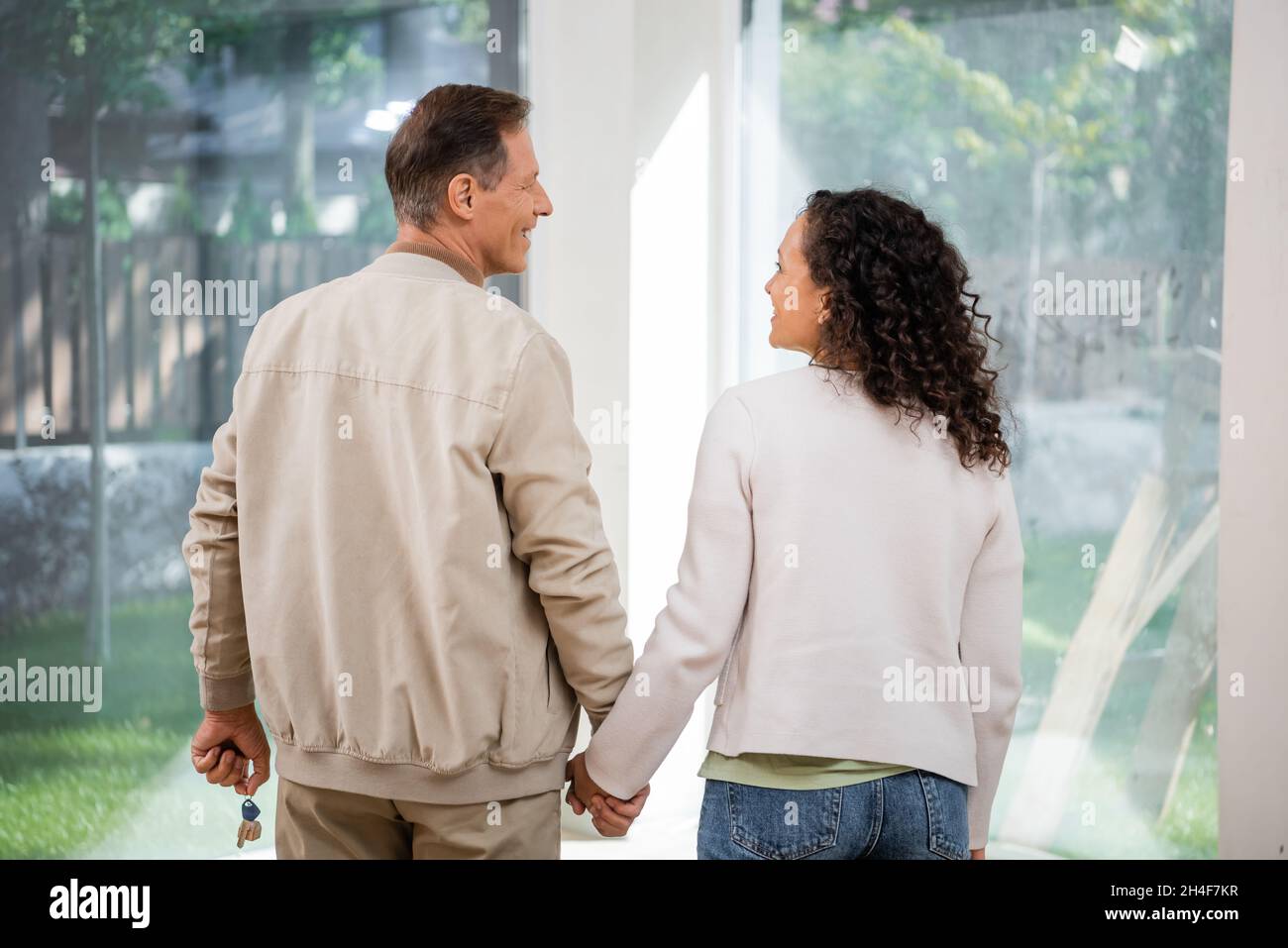 cheerful man holding key and looking at african american wife in new ...