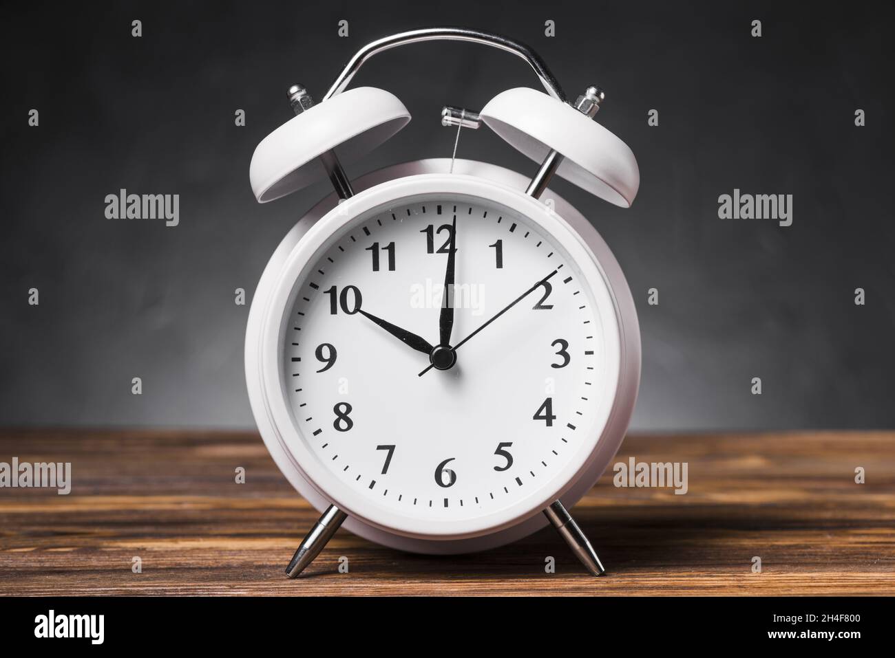 white alarm clock wooden textured table showing 10 oclock. Resolution