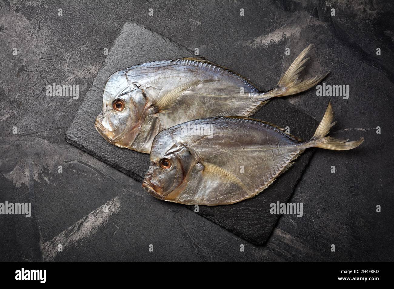 Top view of tasty salty dried sea fish vomer or Selena on slate board