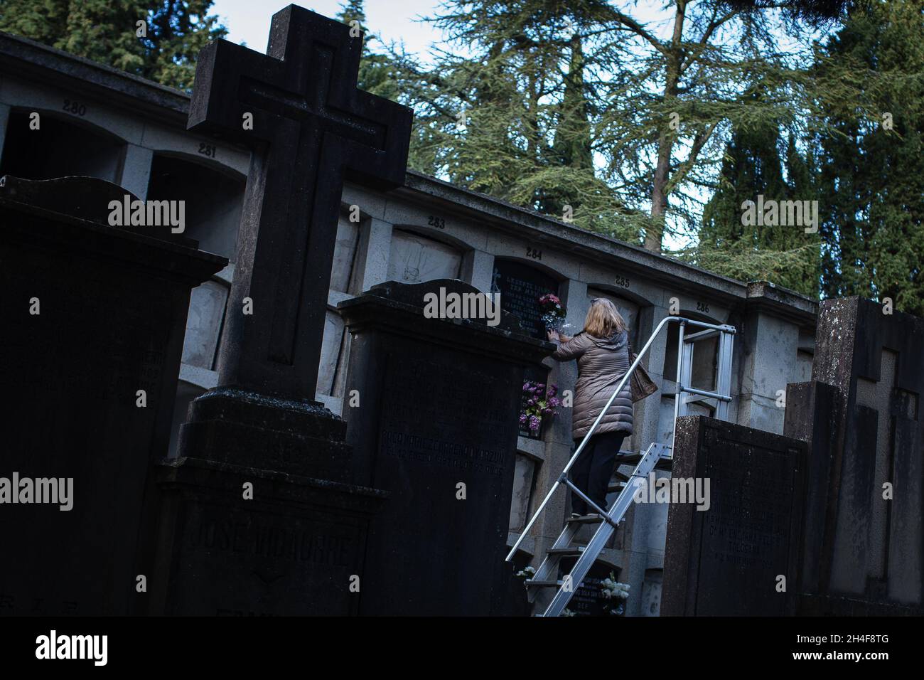 Pamplona, Spain 1 Nov 2021, A woman cleans the grave stone of a
