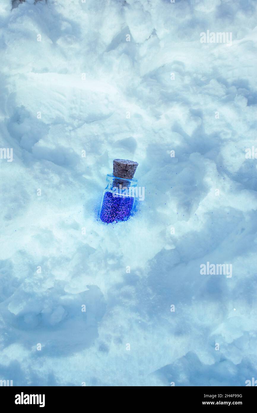 Grass bottle full of glitter buried in snow with copy space Stock Photo