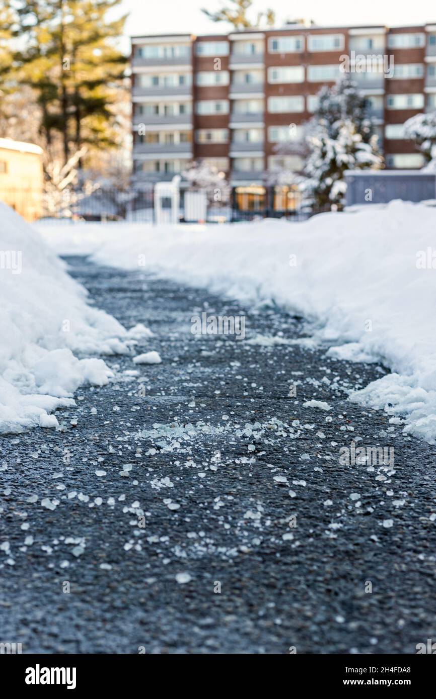 Winter road with salt for melting snow and house in background Stock