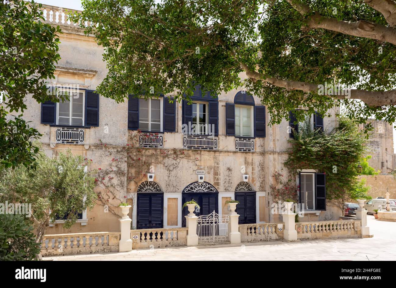 Picturesque house in Mdina, Malta, with navy blue door and windows shutters, with snowy white mouldings and fence door gate. Stock Photo