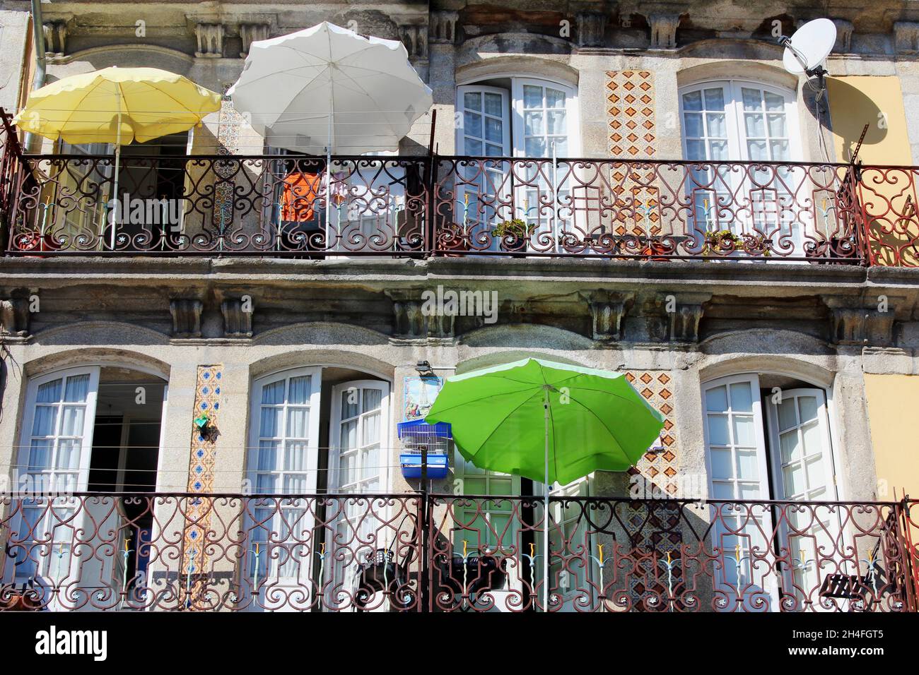 Gelbes Haus mit Sonnenschirmen auf den Balkonen in Porto, Portugal. Stock Photo