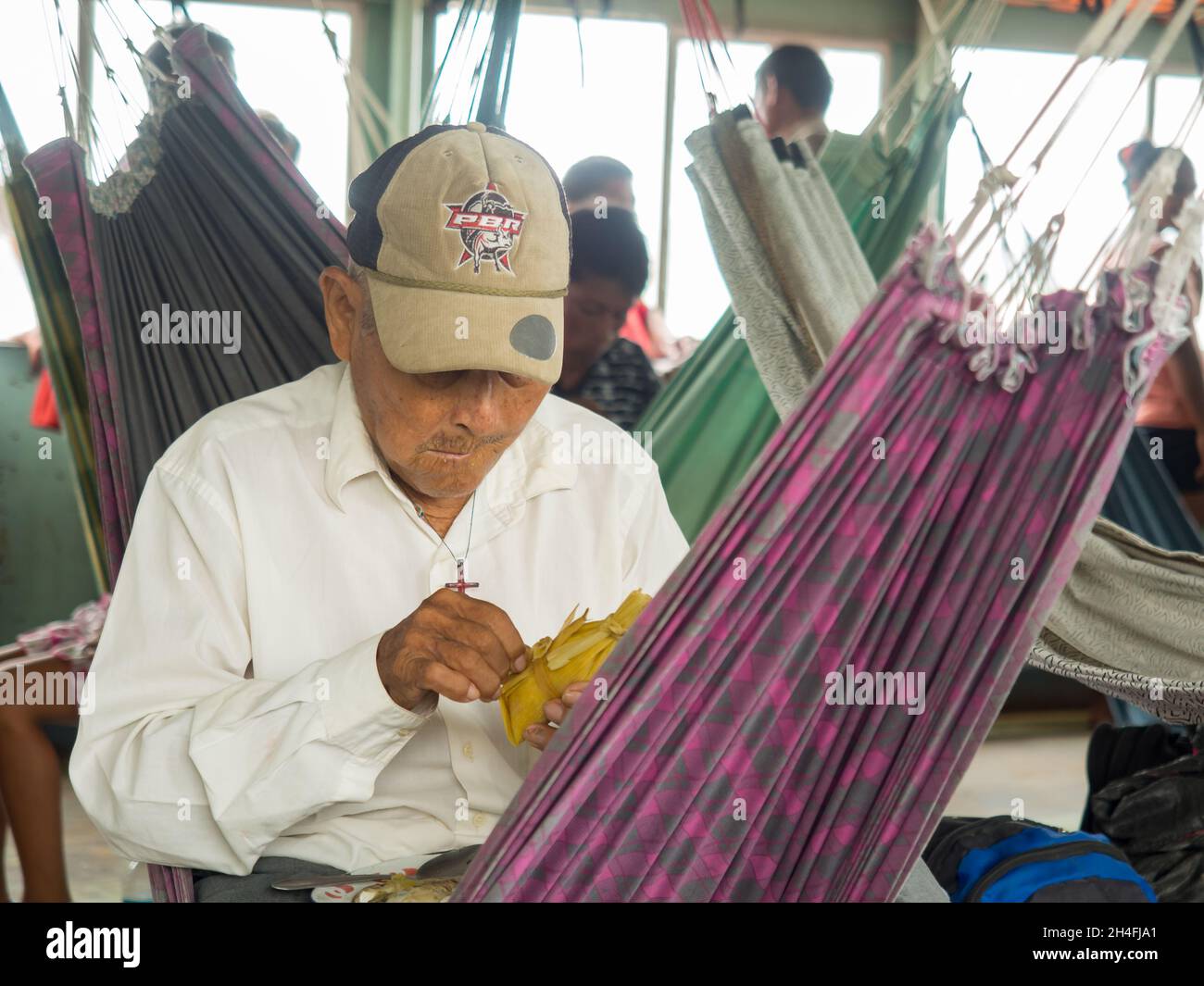 Amazon, Peru - September 2017: Grandma sit in hammock and eat on the deck of a cargo boat. Amazonia. South America Stock Photo
