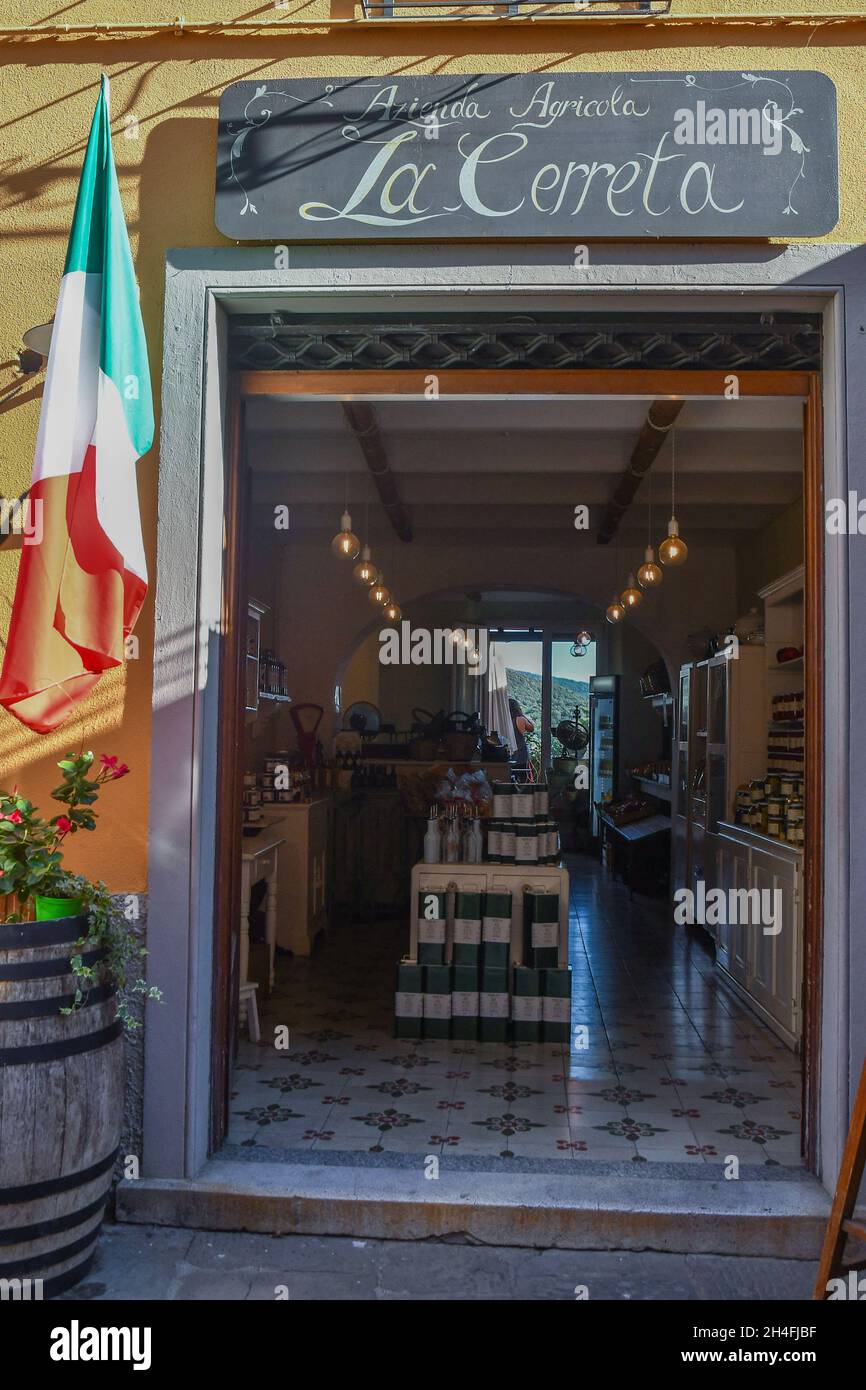 Entrance of a shop selling typical local products in the medieval village of Castagneto Carducci with an Italian flag hanging on the wall, Livorno, Stock Photo