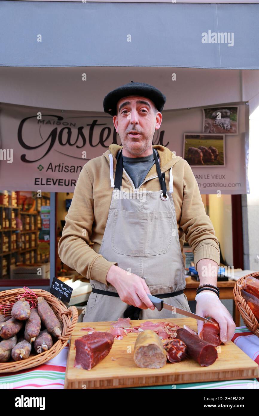 A Pays Basque stallholder slicing his salamis up for sale at the Fete du Piment, Pyrenees Atlantic, France Stock Photo