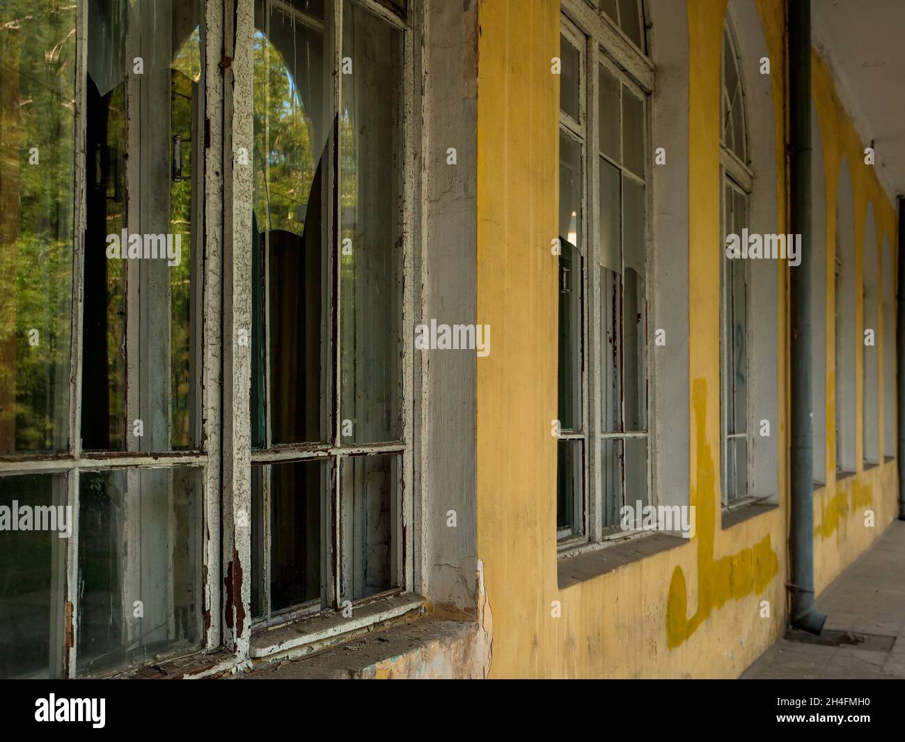 Long passage along the old abandoned building with high french windows with broken glasses. Stock Photo