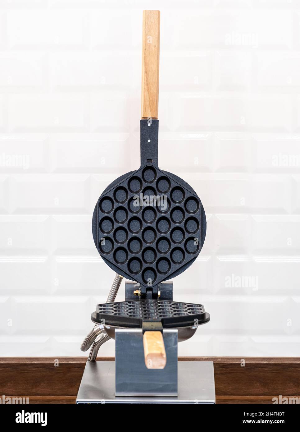Electric bubble waffle iron on a wooden background. Stock Photo