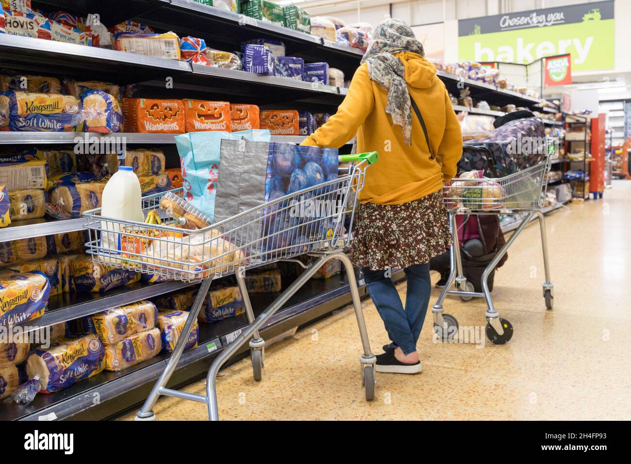 Shoppers pick bread at bakery isle for weekly essential shopping