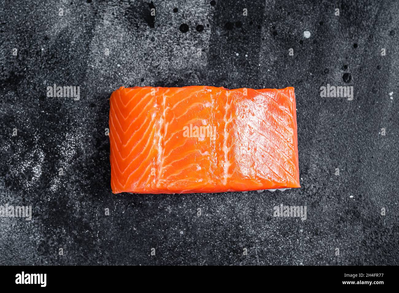 Raw salmon fillet steaks on kitchen table. Black background. Top view ...