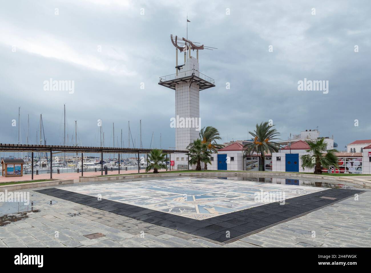 partial view of the grau of Castellón de la Plana, mosaic in the foreground and the promenade of the port with the rectangular tower, Spain Stock Photo