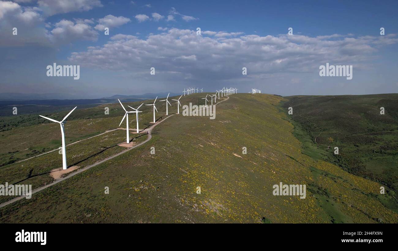 drone view of a wind turbine farm on top of a mountain with grass and a ...